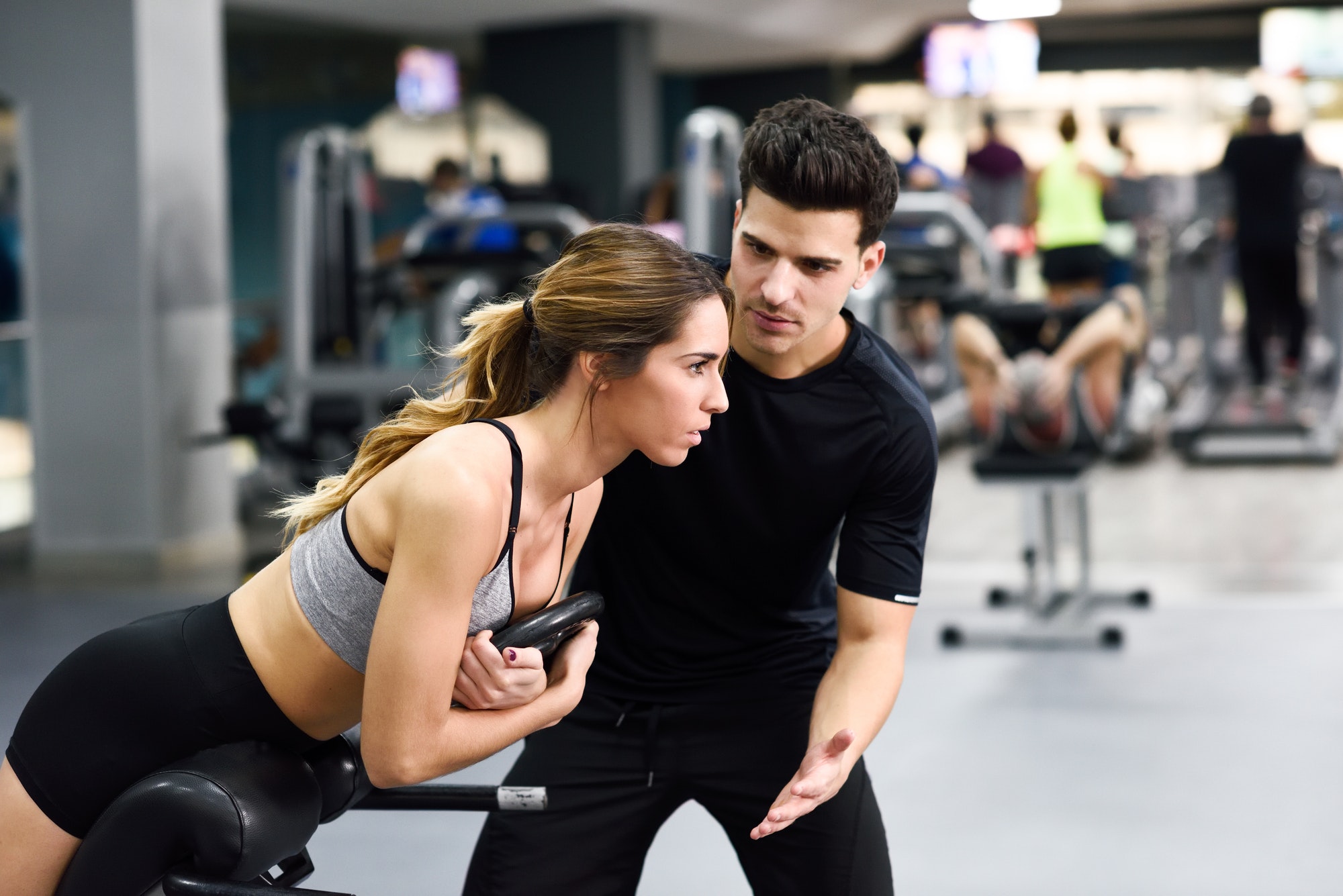 personal-trainer-helping-young-woman-lift-weights.jpg