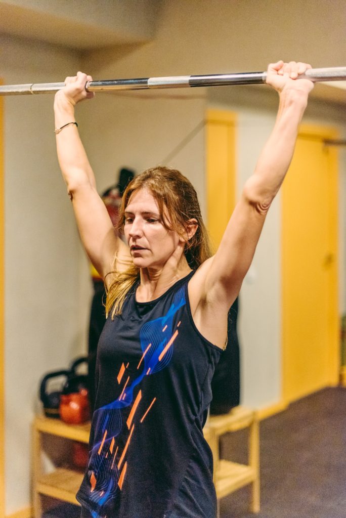 Athlete woman doing press exercise with bar in the gym